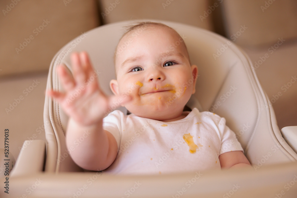 Cheerful baby boy playing in high chair after meal Cheerful baby boy playing in high chair after meal