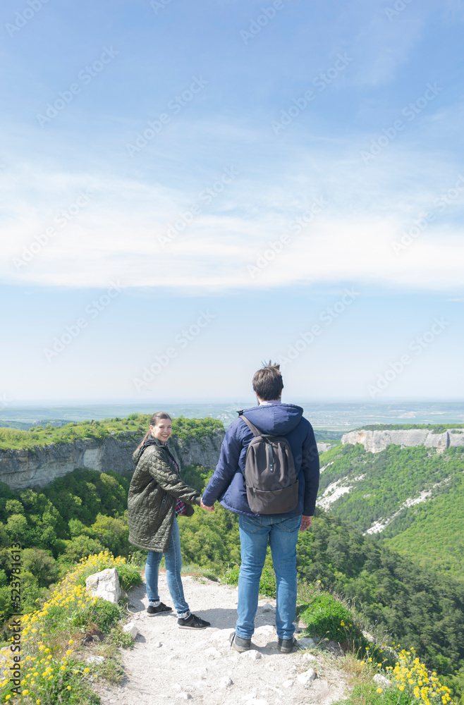 Couple of male and female tourists hold each other's hands as they reached the top and enjoy the view. Adventure hiking hiking hiking. Top. Man with a backpack