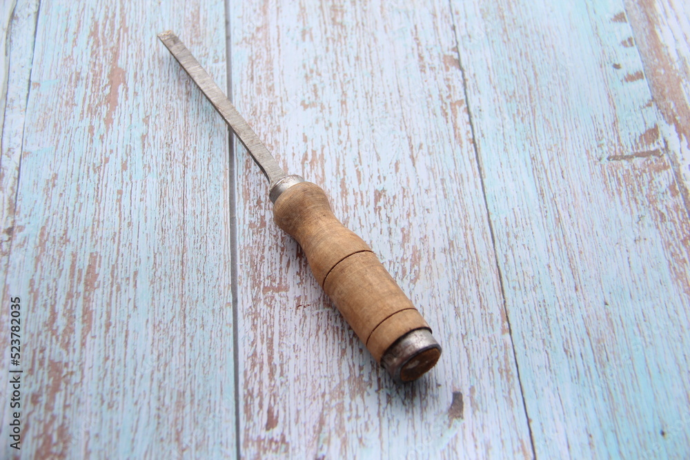 Chisel with wooden handle, isolated on a wooden table, top view, space for text.