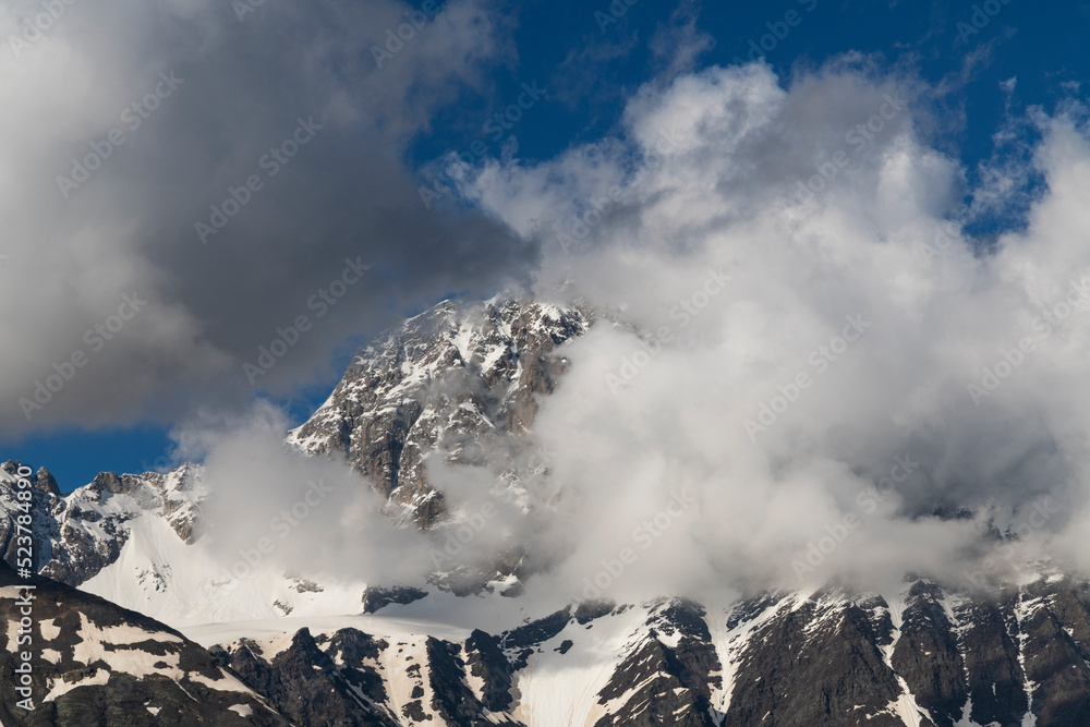 Clouds over the snow covered mountains. High mountains peak. Beautiful winter landscape.