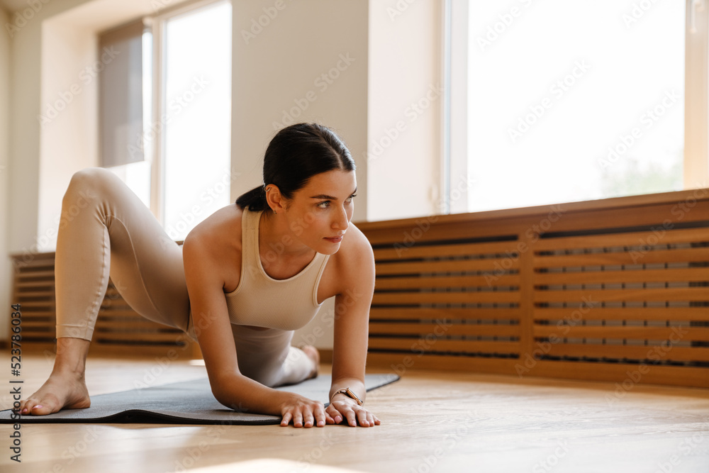 Obraz premium Young white woman doing exercise on mat during yoga practice