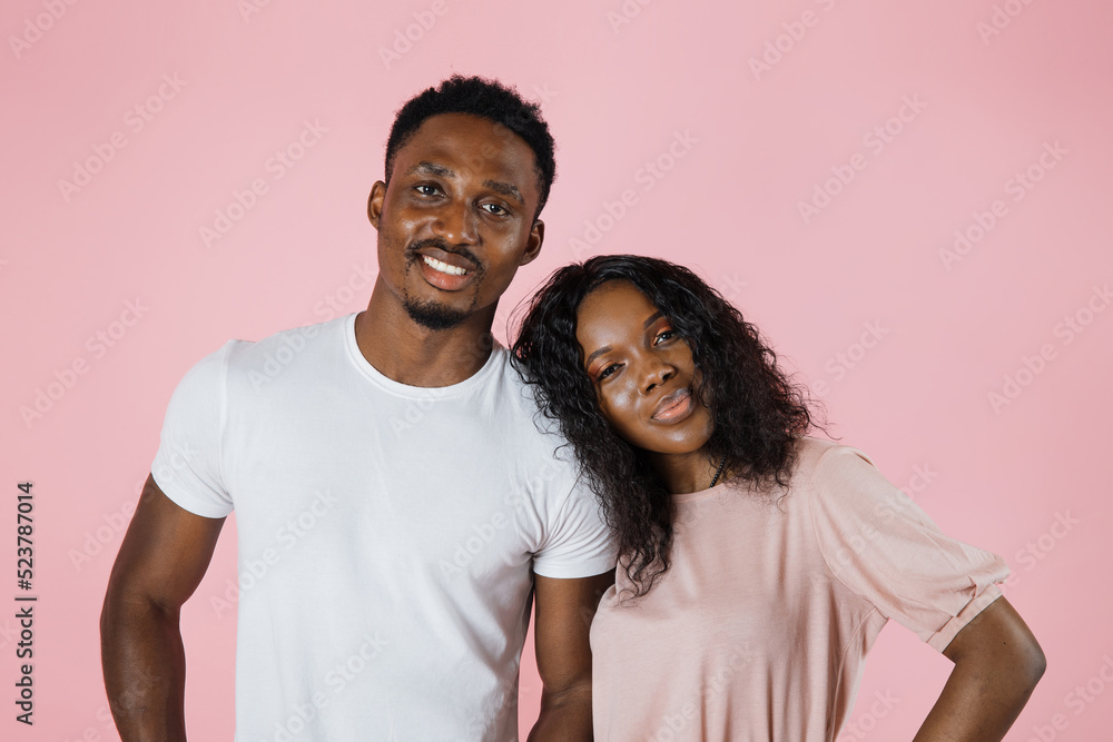 Close up portrait of smiling beautiful african woman and her handsome boyfriend. Happy cheerful family having tender moments near pink wall in studio.Pure cheerful models hugging, embracing each other Close up portrait of smiling beautiful african woman and her handsome boyfriend. Happy cheerful family having tender moments near pink wall in studio.Pure cheerful models hugging, embracing each other