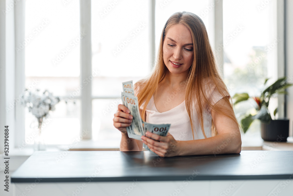 Blonde long-haired woman counting money at home Blonde long-haired woman counting money at home