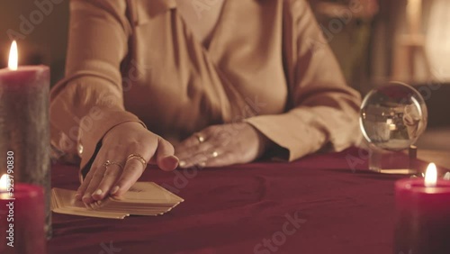 Cropped slowmo of unrecognizable fortune teller using tarot cards while predicting future to client at seance photo