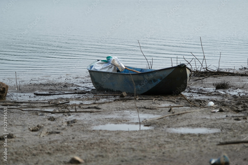 Old boat on the bank of the river among the twigs waste.