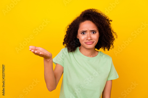Photo of shocked confused girl dressed green t-shirt rising arm isolated yellow color background
