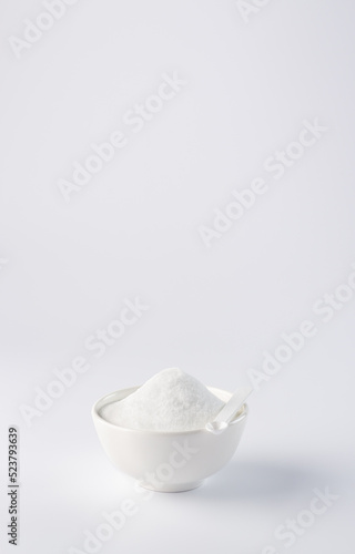 Sugar substitute. Vertical photo of a sugar substitute on a white background in a white bowl. Small spoon in a bowl. Stevia.