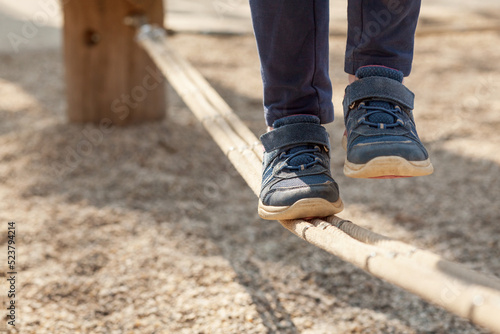 Stackline for Children on Playground. Child Girl Legs on Slackline. Strength and Balance Exercises