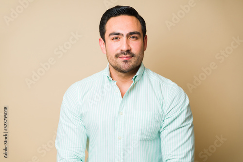 Portrait of a handsome smiling man looking at the camera in front of a studio background