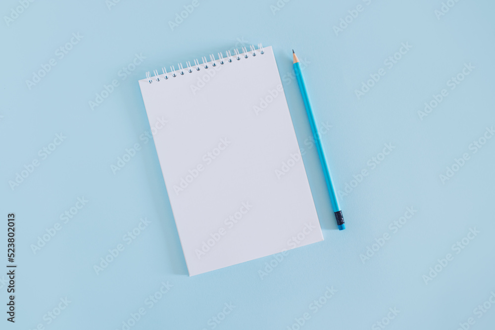 Notebook with blank page and pencil on light blue background. Notebook with blank page and pencil on light blue background.