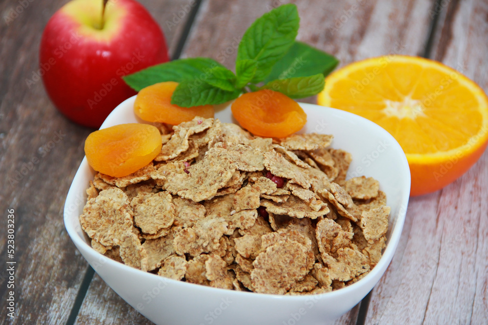 dry diet muesli in a white plate, orange slice, red apple and dried apricots dry diet muesli in a white plate, orange slice, red apple and dried apricots