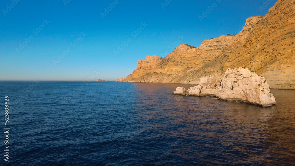 Sierra Helada cliffs and Mitjana island from the sea, aerial view, Benidorm, Alicante province, Spain