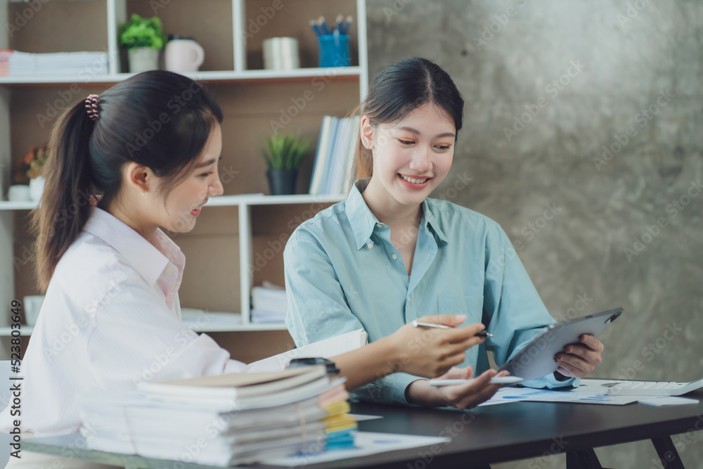 Smiling young Asian businesswomen talking to colleague and exchanging ideas together at office. Smiling young Asian businesswomen talking to colleague and exchanging ideas together at office.