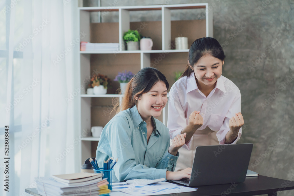 Two young Asian businesswoman discuss investment project working and planning strategy. Business people talking together with laptop computer at office. Two young Asian businesswoman discuss investment project working and planning strategy. Business people talking together with laptop computer at office.