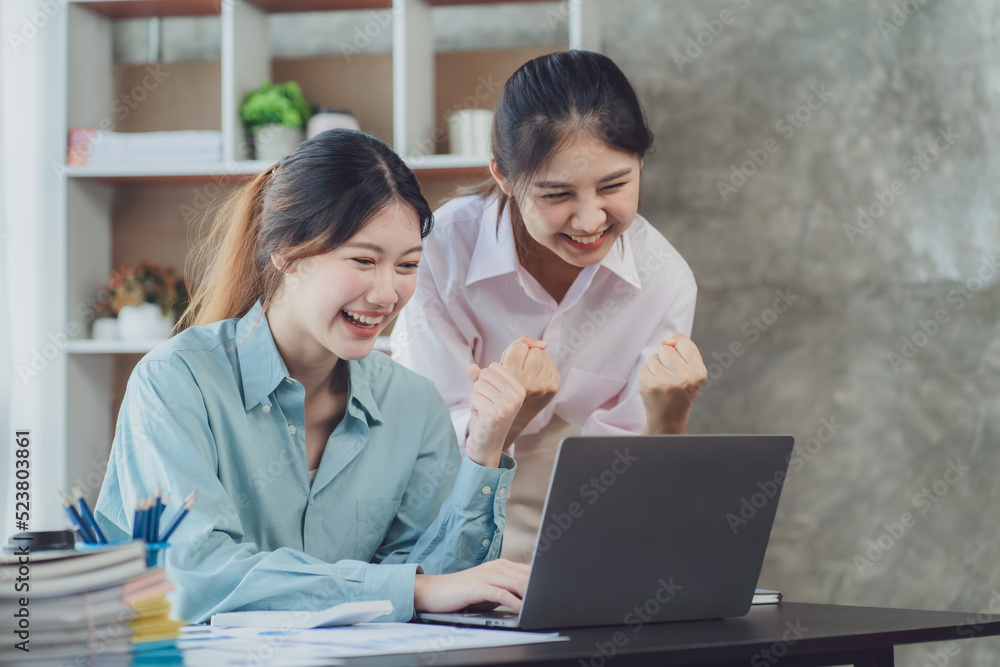 Two young Asian businesswoman discuss investment project working and planning strategy. Business people talking together with laptop computer at office. Two young Asian businesswoman discuss investment project working and planning strategy. Business people talking together with laptop computer at office.
