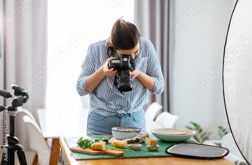 blogging, profession and people concept - female photographer with camera photographing food in kitchen at home