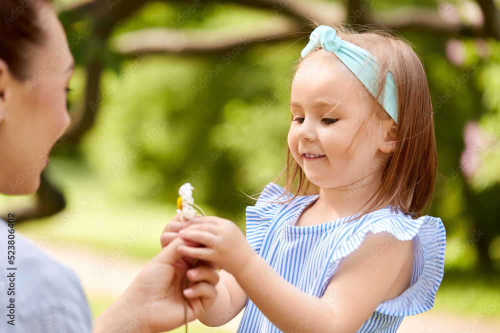 family, motherhood and people concept - happy mother and little daughter with chamomile flower at summer park or garden family, motherhood and people concept - happy mother and little daughter with chamomile flower at summer park or garden