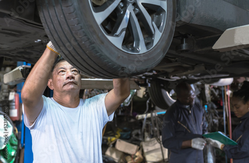 Asian mechanic man changing tire at auto repair shop, technician man working and checking car tire problems at car service 