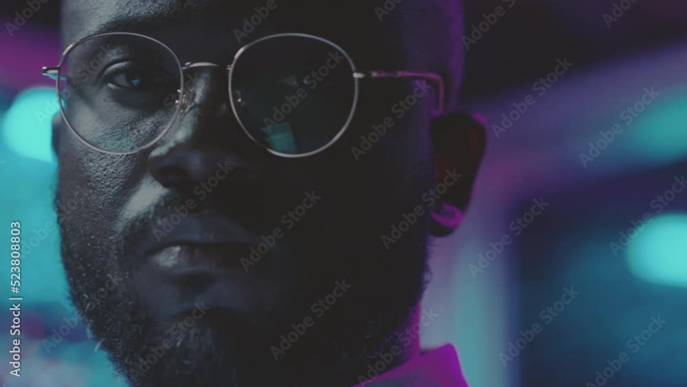 Portrait of African American man posing for camera in dark server room while working as network administrator in data center Portrait of African American man posing for camera in dark server room while working as network administrator in data center