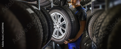 Fotografia Hardworking experienced worker holding tire and he wants to change it In the tire store