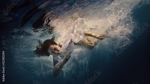 A girl with long dark hair swims underwater as if flying