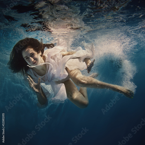 A girl with long dark hair swims underwater as if flying