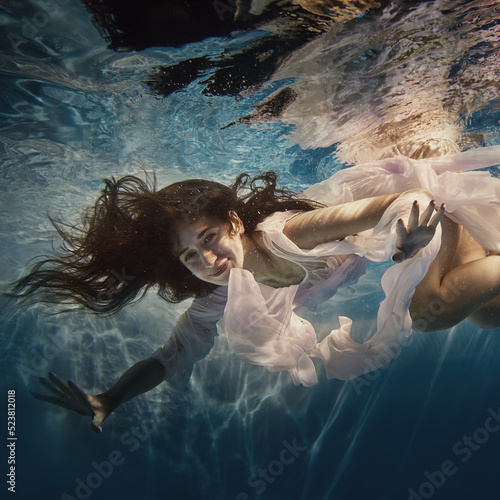 A girl with long dark hair swims underwater as if flying