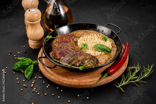 Dish of grilled meat, sauce and rice on wooden background
