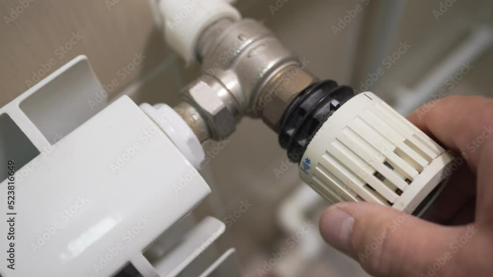 Person turns off of thermal energy on the heating radiator. Saving energy by adjusting heating thermostat. Person turns off of thermal energy on the heating radiator. Saving energy by adjusting heating thermostat.