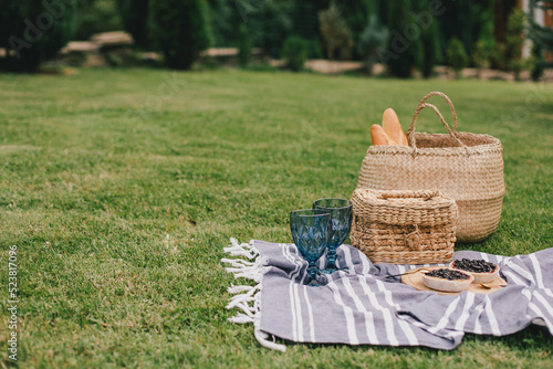Fototapeta Naklejka Na Ścianę i Meble -  Beautiful romantic picnic with cake and two glasses of wine on the green meadow.