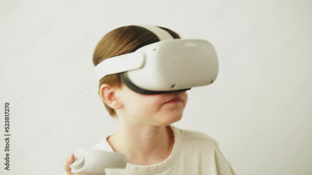 Boy using virtual reality glasses with controllers, playing video games, child gamer wearing new generation gaming headset for entertainment and education, future technology concept. Boy using virtual reality glasses with controllers, playing video games, child gamer wearing new generation gaming headset for entertainment and education, future technology concept.