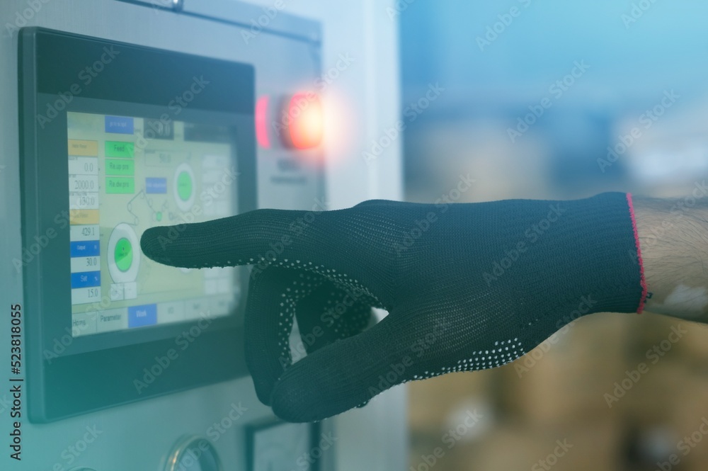 Worker hand in a black glove presses on the touch screen control panel ...