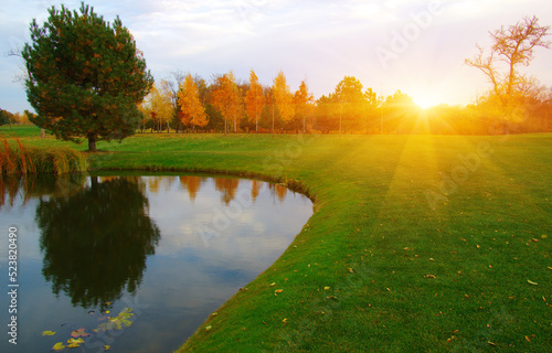 Autumn landscape with lake, green grass and colourful trees
