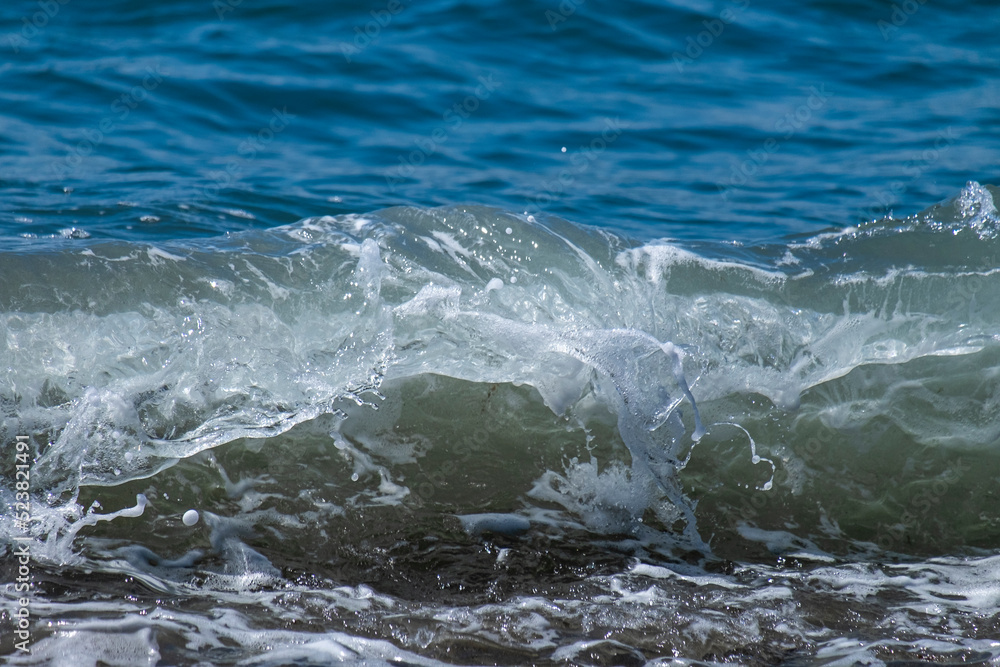 Ocean waves crashing on sandy beach. Sea waves breaking on shore.