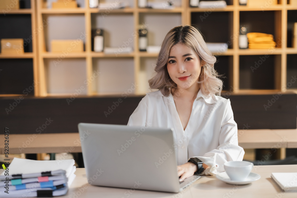 Beautiful Asian portrait businesswoman manager smile workingin office with a laptop in the modern office sitting online marketing financial communication. Beautiful Asian portrait businesswoman manager smile workingin office with a laptop in the modern office sitting online marketing financial communication.