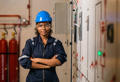 Professional engineer black women working with tablet at warehouse factory. Engineer Worker Wearing Safety Uniform and Hard Hat. Female  checking at electrical cabinet control.
