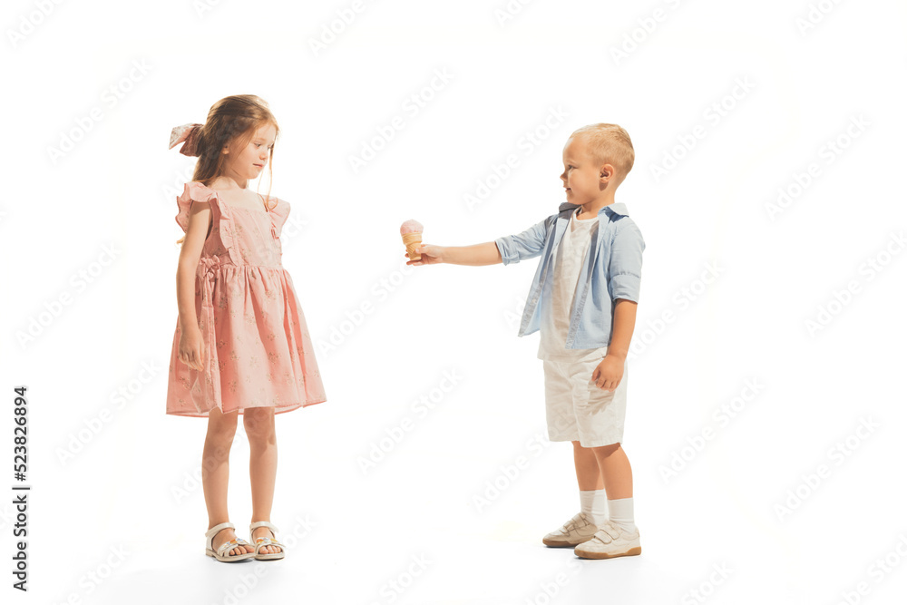 Portrait of children, little boy giving ice cream to beautiful girl isolated over white studio background Portrait of children, little boy giving ice cream to beautiful girl isolated over white studio background