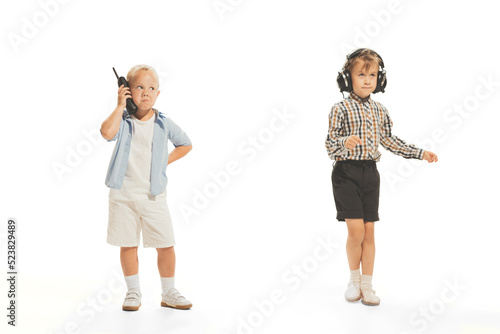 Portrait of little boys, children playing together, talking on phone, dancing isolated over white studio background