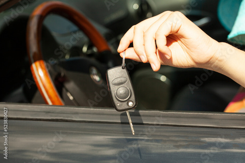 Car key in woman's hand with car.