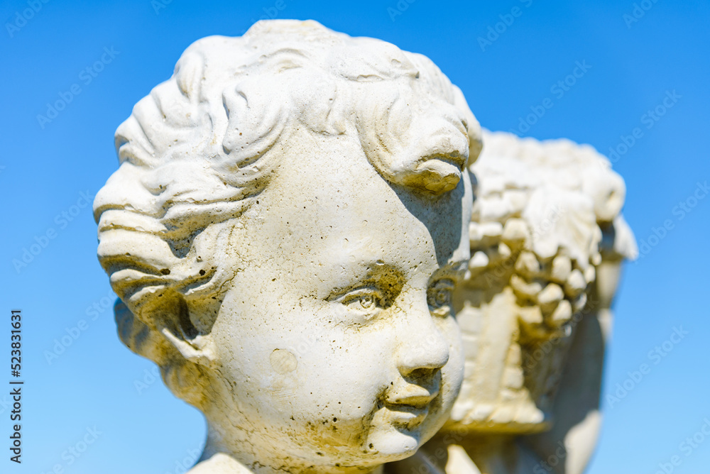 Closeup of a ancient young boy statue at summer park.Close-up.