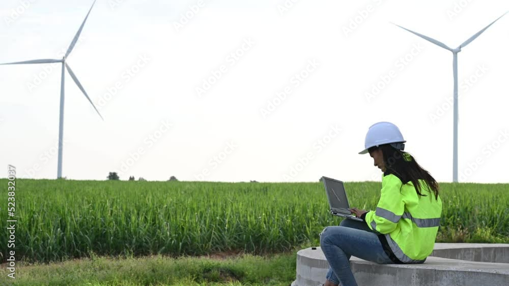 women engineer working and holding the report at wind turbine farm Power Generator Station on mountain,Thailand people women engineer working and holding the report at wind turbine farm Power Generator Station on mountain,Thailand people