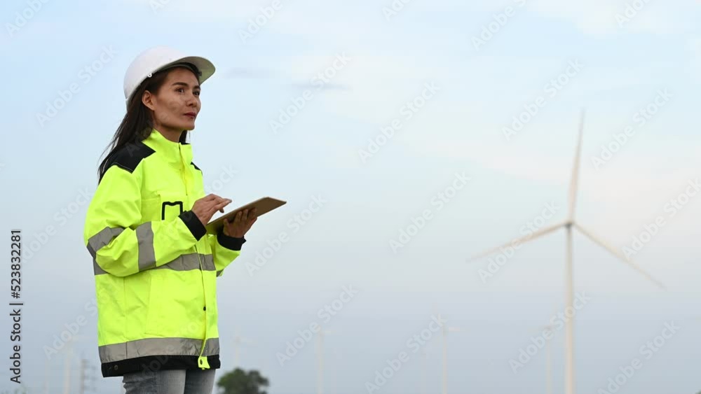 women engineer working and holding the report at wind turbine farm Power Generator Station on mountain,Thailand people women engineer working and holding the report at wind turbine farm Power Generator Station on mountain,Thailand people