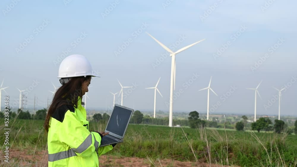 women engineer working and holding the report at wind turbine farm Power Generator Station on mountain,Thailand people women engineer working and holding the report at wind turbine farm Power Generator Station on mountain,Thailand people