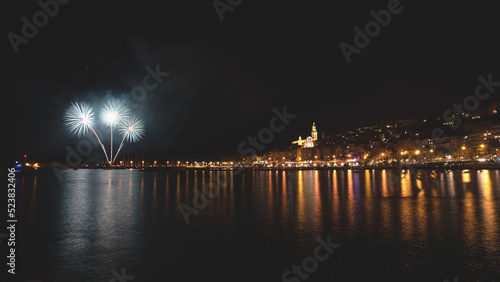 Feu d'artifice du 15 août pour les fêtes de l'assomption à Menton avec les reflets des lumières de la ville sur la mer