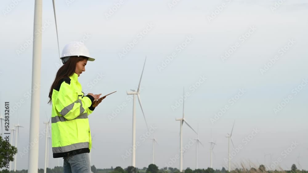 women engineer working and holding the report at wind turbine farm Power Generator Station on mountain,Thailand people women engineer working and holding the report at wind turbine farm Power Generator Station on mountain,Thailand people