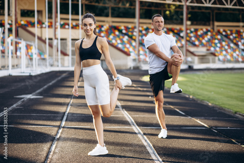 Woman and man stretching at the stadium before jogging