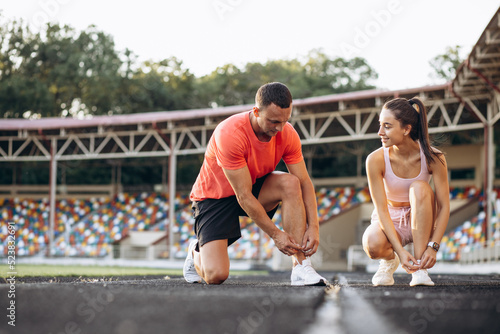 Man and woman tiying laces on their sneakers