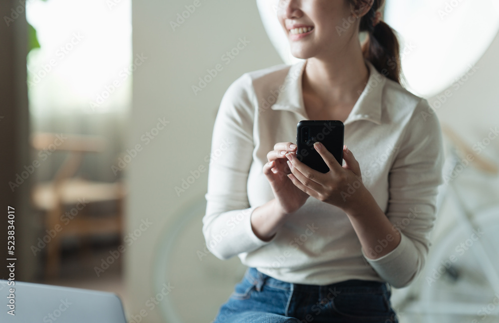 Charming woman with beautiful smile reading good news on mobile phone during rest in coffee shop