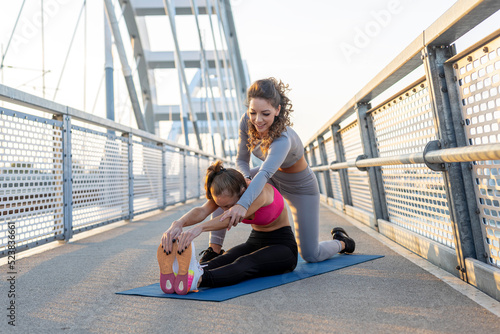 Two young woman exercise and stretch before jogging on the bridge