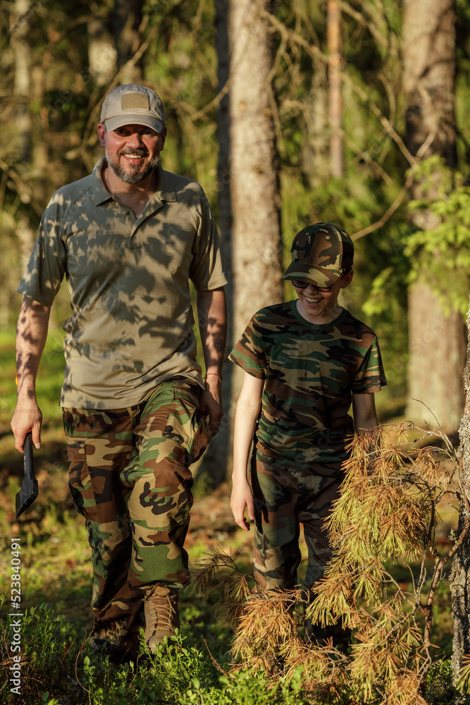 Father and son in military clothes spending time together in the woods. The concept of adventure, travel, tourism and camping